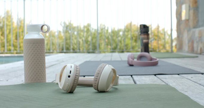 Opening with camera remaining steady on balcony deck showing headphones on green mat and pink band