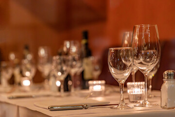 Dinner table with wine bottle, glasses and plates, knife in a cozy and warm atomsphere