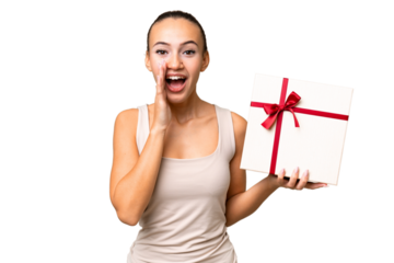 Young Arab woman holding a gift over isolated background shouting with mouth wide open