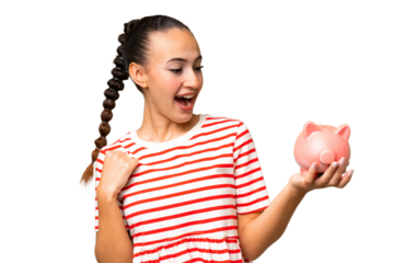 Young Arab woman holding a piggybank over isolated background celebrating a victory