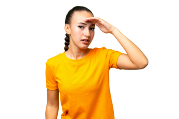 Young Arab woman over isolated background looking far away with hand to look something