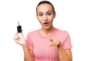 Young Arab woman holding car keys over isolated background surprised and pointing front