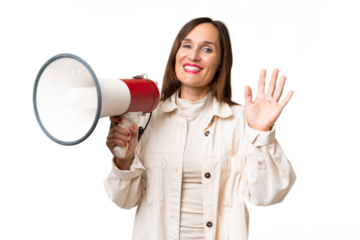 Middle-aged caucasian woman over isolated background holding a megaphone and saluting with hand with happy expression