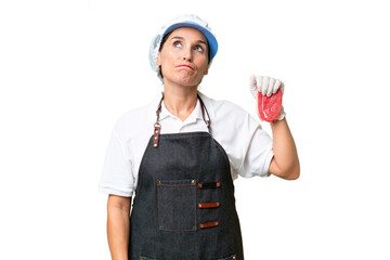 Butcher woman wearing an apron and serving fresh cut meat over isolated background and looking up