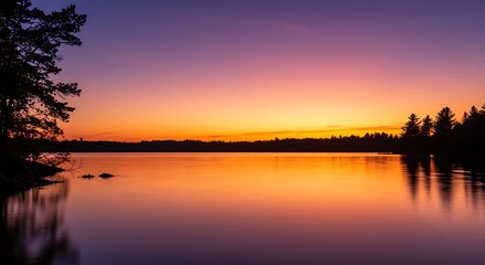 Obraz premium Serene lake reflects vibrant sunset hues, silhouetting trees against a dramatic, colorful sky