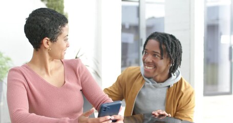 Diverse couple sharing playful hug at table with man approaching after smartphone scrolling at home - Powered by Adobe