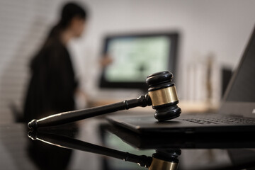 A focused Asian female judge works on complex cases involving cyber law, data protection, and digital rights, with the gavel and laptop symbolizing modern legal authority.