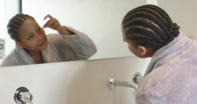 African American woman reaching for brush at sink pressing around nose for cleansing copy space