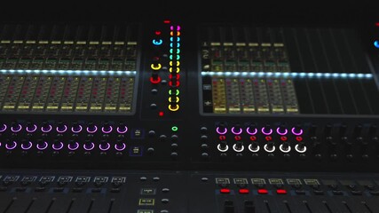 Detailed shot of a professional audio mixing panel with bright colorful LED lights and controls.
