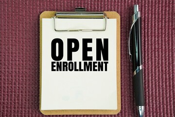 Pen and whiteboard paper with the words Open Enrollment. a period of time during which you can join something as a member or participant