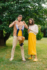 Fototapeta premium Father Lifting Son While Pregnant Mother Watches