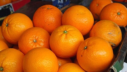 A close-up reveals a vibrant heap of ripe, juicy oranges, their skins glowing with sunny citrus hues
