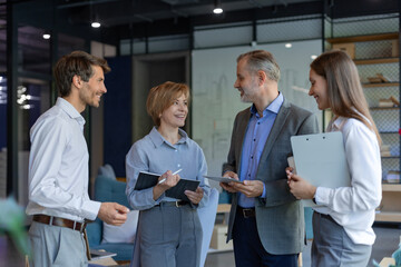 Four business people discussing work together using a tablet in a modern office
