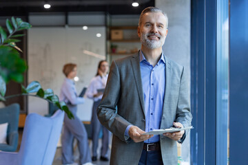 Smiling handsome businessman manager standing in office with tablet
