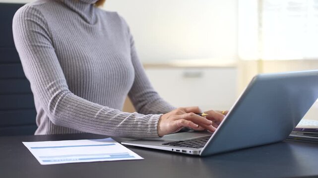 Business woman working on laptop and accounting financial report, accountant using calculator to calculate tax refund at office
