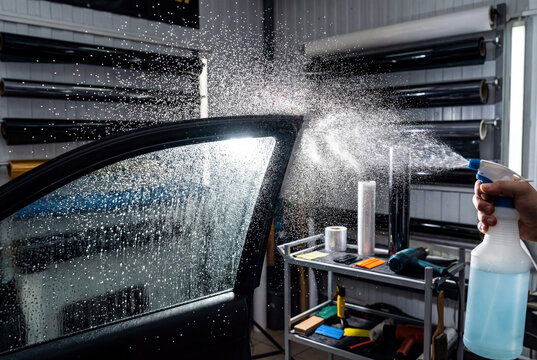 Spraying soapy water on car window glass before applying tint film or cleaning