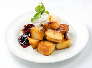 Delicious French toast cubes dusted with powder sugar, served with vanilla ice cream, berry jam, and fresh mint on a clean white plate