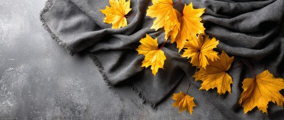 Autumn leaves on a gray fabric surface create a warm seasonal atmosphere in a cozy setting