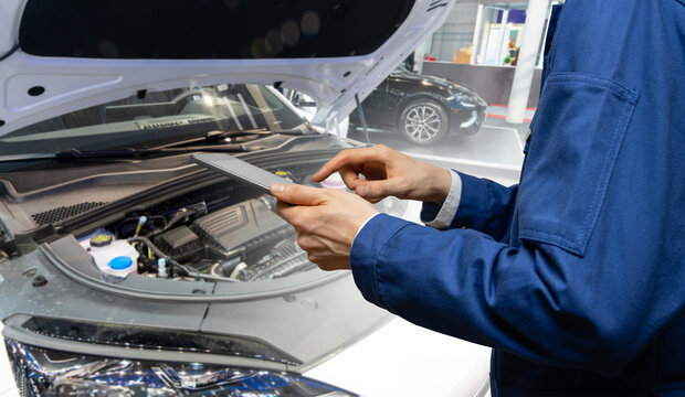 Serviceman with digital tablet on the background of the car in the car service