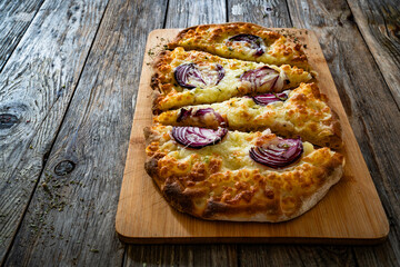 Pinsa bianca white pizza with red onion and oregano on wooden table	