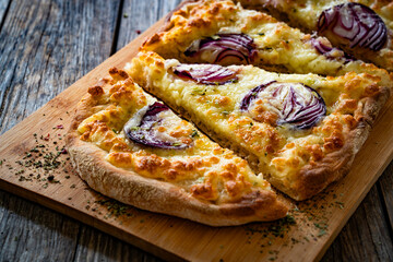 Pinsa bianca white pizza with red onion and oregano on wooden table	