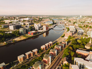 Newcastle upon Tyne: 9th August 2025: Buildings line the Newcastle Quayside at dawn. Bridges stands over the river, reflecting in the water below. Drone view from Ouseburn