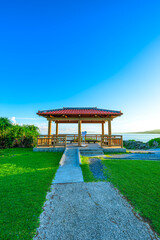  真栄田岬の海を望む赤瓦屋根の東屋と青空の美しい風景