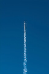 Obraz premium Minimalist Rocket Launch Leaving White Smoke Trail in Blue Sky