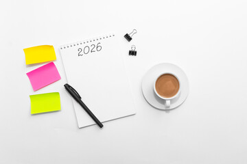 Minimal workspace with notebook, colorful sticky notes, pen, binder clips and coffee cup on white background, top view