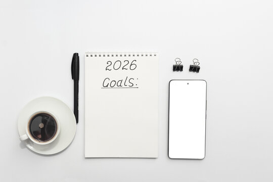Workspace with notebook labeled 2026 Goals, pen, smartphone and coffee cup, top view, minimal and organized - Powered by Adobe