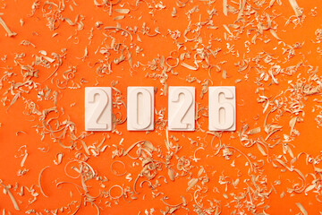 ?lose-up of the white numbers 2026 on a orange background with sawdust