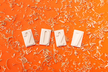 Сlose-up of the white numbers 2027 on a orange background with sawdust