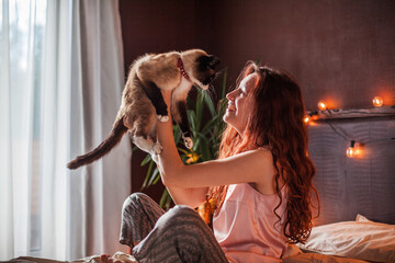 oung Woman hug Cat and sit on Bed in bedroom