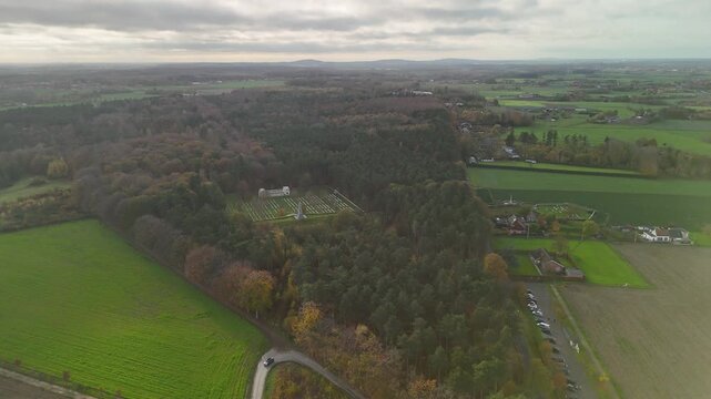 Aerial drone view of Polygon Wood Cemetery and memorial on former First World War battlefields near Ypres, surrounded by dense forest and Flemish countryside.