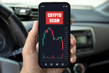 male hand hold phone with chart scam crypto coins car