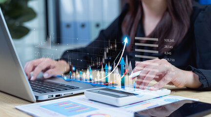 Businesswoman using laptop and calculator to review company growth with upward trend graphics, analyzing financial data, future development, and long-term investment outlook.