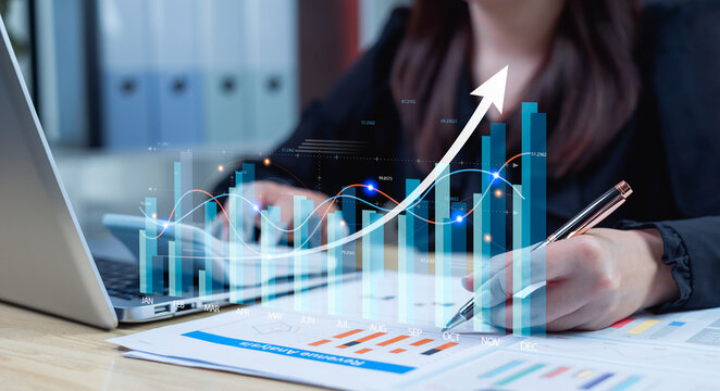 Global business growth concept with businesswoman analyzing holographic economic charts, upward investment indicators, and worldwide financial trend analysis.