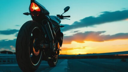 Video A motorcycle parked on the side of the road at sunset, great for travel or adventure themes