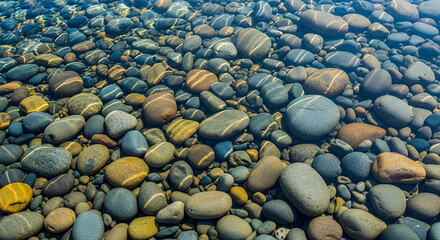Smooth grey and white pebbles and stones on the beach creating a natural texture and abstract pattern