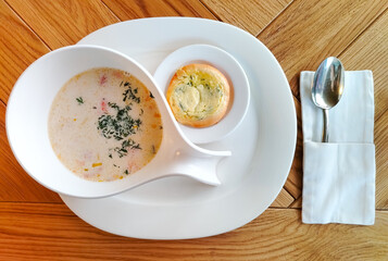 Norwegian fish soup creamy salmon chowder in white bowl on wooden table horizontal