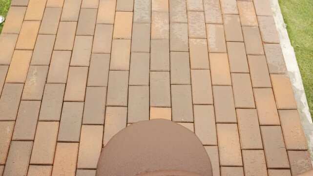 Worker spreading sand over brick paving stones