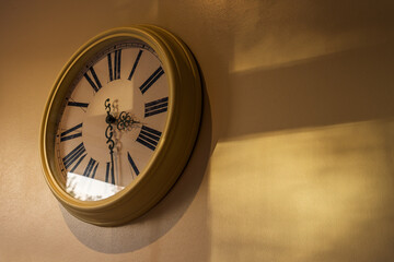 Analogue clock with the last sunlight of the day on the wall, idea of the passage of time or a journey with copy space for your text