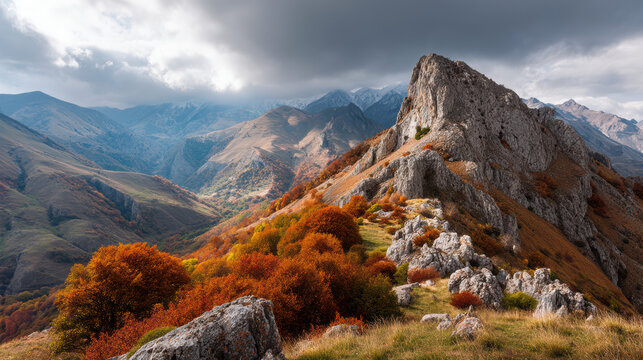 A rugged mountain peak rises majestically against a dramatic cloudy sky, showcasing the vibrant autumn foliage cove the surrounding slopes and valleys below.