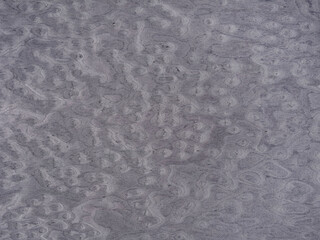 Swirling patterns on a muted gray veneer surface evoke a sense of organic movement