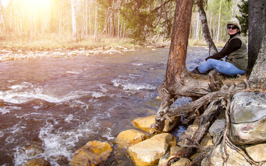 Beautiful women. A tourist sits on the rocky bank of the Birch River flowing into the Yuryuzan River. A sunny spring day.