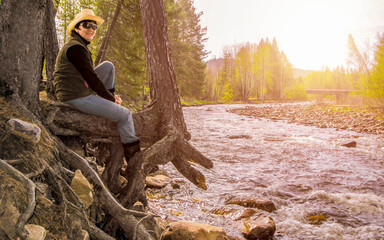 Beautiful women. A tourist sits on the rocky bank of the Birch River flowing into the Yuryuzan River. A sunny spring day.