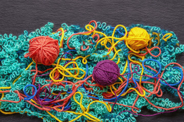 Untangling tangled threads. Multicolored bright tangled threads and  attempt to wind them into balls. Black background, flat lay, copy space
