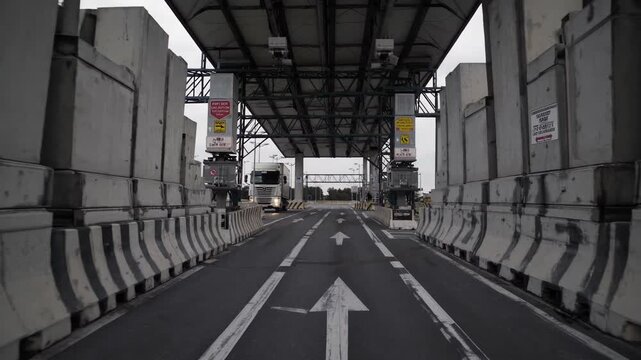 Freight trucks driving towards immigration and customs control barriers at a busy international border crossing, representing global logistics, security checks, and cross border trade