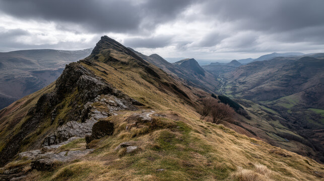 A steep, rocky mountain ridge stretches into the distance under a dramatic, cloudy sky, showcasing the rugged beauty of the mountainous landscape perfectly.