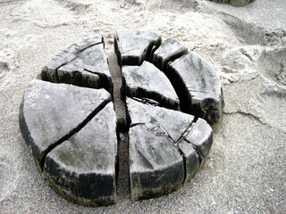 Aufsicht auf eine tief im Sand steckenden Buhne aus verwittertem  Holz